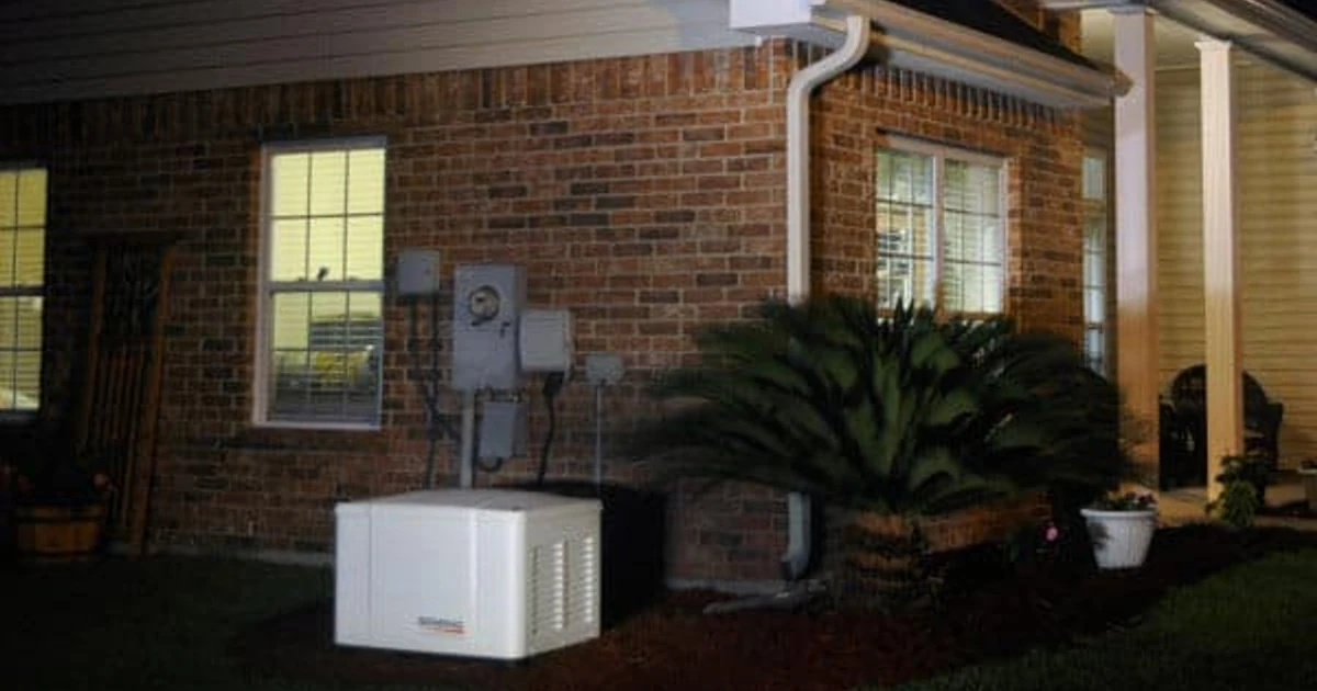 an Automatic Generac PowerPact 7.5kW Home Standby Generator Outside a Home at Night. The lights on are during a power outage thanks to the Generator